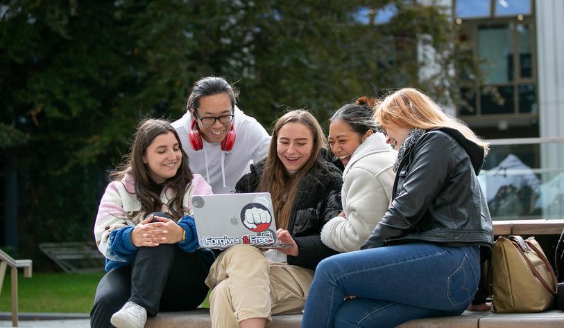 Students laugh while looking a laptop