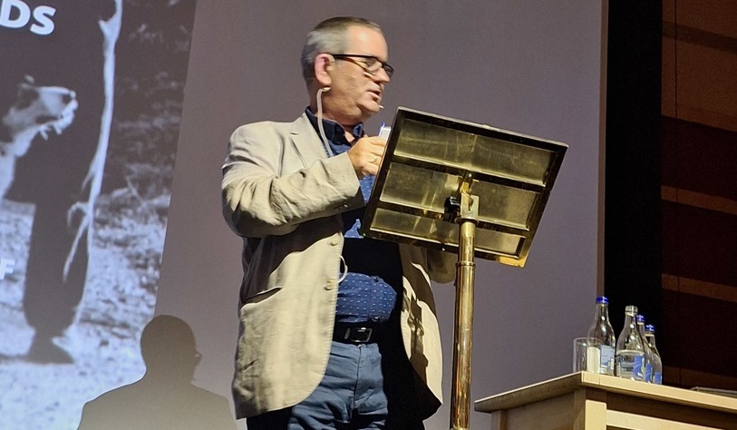 A person speaking at a gold lecturn