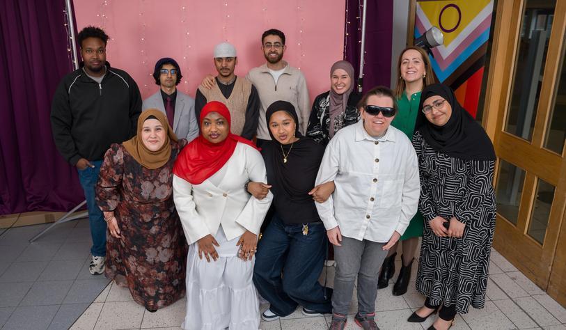 A group of people pose for a photo smiling and cheering