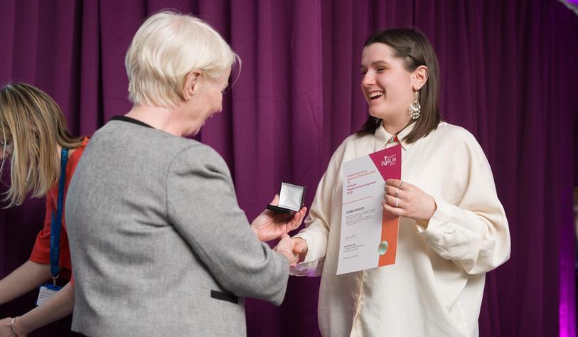 One person hands another person a little box with a medal
