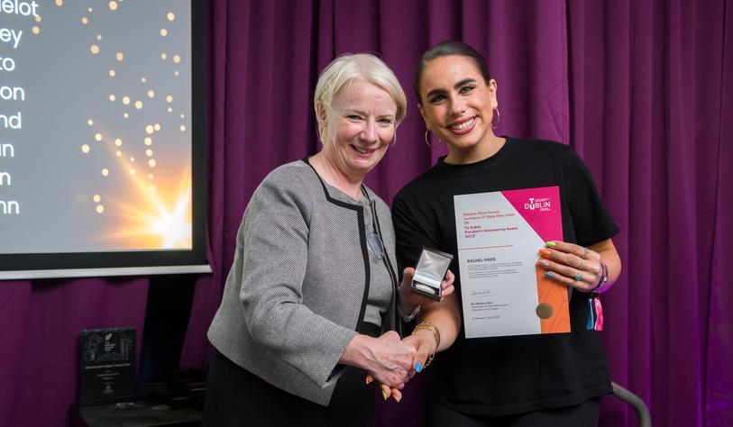 Two people shake hands and smile, with one person holding a certificate
