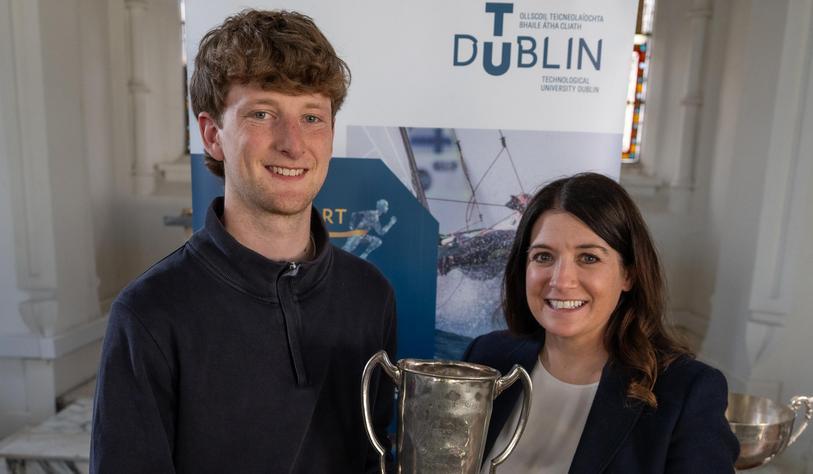 Two people smiling and holding trophies