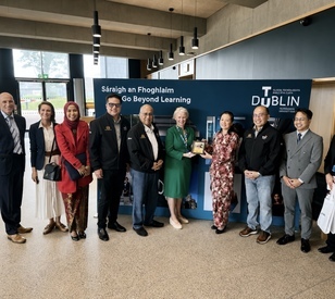 Group of nine people standing together at TU Dublin’s Grangegorman campus, with representatives from Malaysia and TU Dublin posing in front of a TU Dublin “Go Beyond Learning” display.