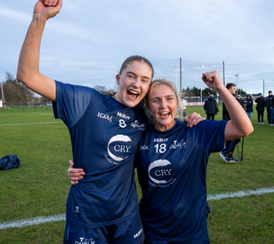 Two people in sporting clothing celebrate on a grass field