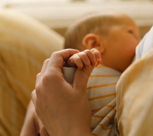 Newborn baby drinking milk from mothers breast. Portrait of mom and breastfeeding baby.