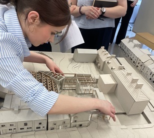 A TU Dublin student examines a detailed scale model of Granard town centre, featuring building layouts and proposed streetscape designs.