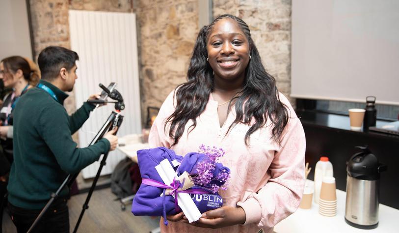 a person posing with a purple jumper and flowers