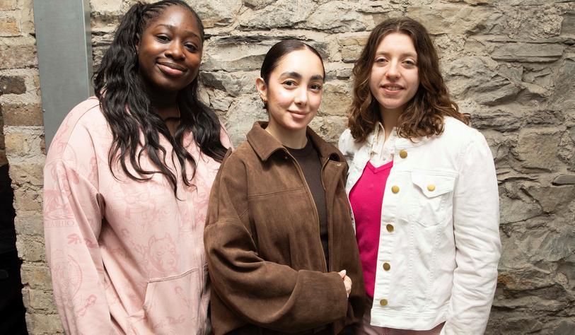 A group of students pose in front of a brick wall