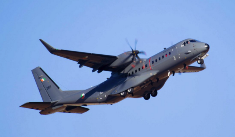 An Irish Air Corps military transport aircraft flies through a clear blue sky.