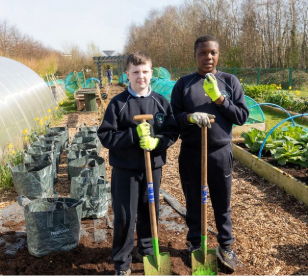 Two pupils holding shovels in a garden