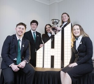 A group of five people in formal attire pose around an illuminated 