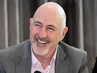 Photograph of a man smiling with microphone in his hand