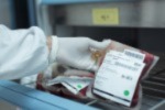 Selective focus scientist hand holding red blood bag in storage blood refrigerator