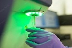 A person holding laboratory equipment under a green light